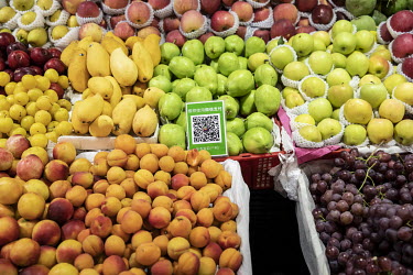 A WeChat payment code sits amongst fruits on sale at a market.