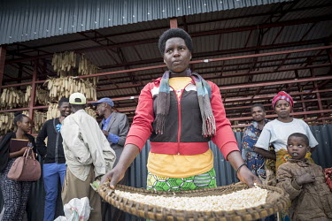 Claire Uwimana uses a wicker basket to shake up maize kernels so that the wind takes the loose husks with it. Farmers at work at a central collection point, where harvested maize is dried, tested and...