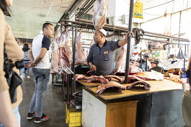 A butcher sells lamb at a market.
