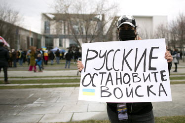 A Ukrainian activist in front of the Chancellor's office holding a placard decrying the Russian military invasion of Ukraine.