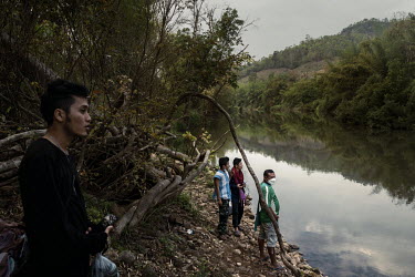 John Henry Newman (left), a member of the KNDO ethnic armed group and the PDF (People's Defence Force), waits on the banks of the Toei River in Thailand with other people from Karen ethnic armed group...