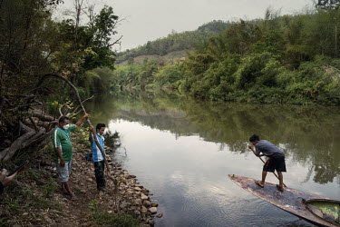 Luther Htoo (centre), a member of the KNDO ethnic armed group, waits on a bank of the Toei River in Thailand to be smuggled across the river into Myanmar.