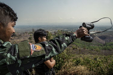 Min Thar (right), a former banquets and events worker at the Lotte Hotel in Yangon who joined the People's Defence Force (PDF), looks over Myanmar Army frontline positions from the closest frontline d...