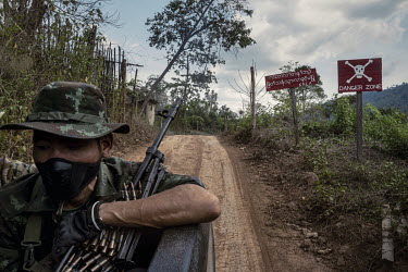A DKBF, Karen ethnic armed group, soldier rides in the back of a pickup truck past signs that read: 'Danger Zone', at the entrance to KNLA, another Karen ethnic armed group's territory, in an undisclo...