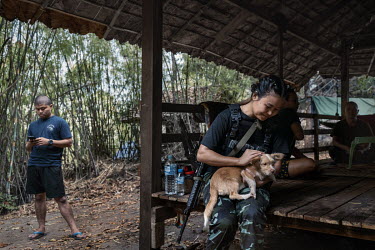 Naw Htee Mupaw, a sergeant in the KNPF, a Karen ethnic armed group, pets a dog as she sits with People's Defence Force (PDF) soldiers on a PDF base in an undisclosed location in Karen State.
