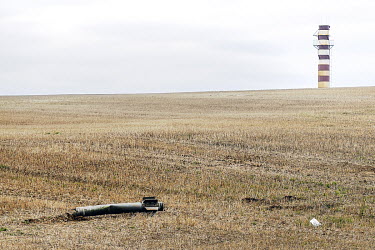 The remnants of a rocket casing lying on an agricultural field.
