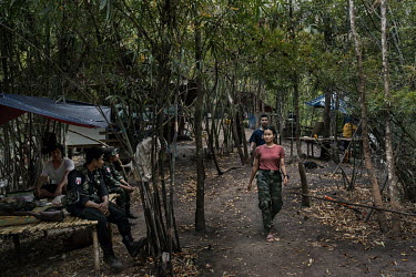 Jolie (front), a former marketing executive, and Ko Thant (behind), who defected from the Myanmar Army, both of whom joined the People's Defence Force (PDF), walk through their PDF camp in an undisclo...
