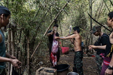 A soldier from the KNLA, an ethnic armed group, demonstrates to People's Defence Force (PDF) soldiers how to skin and butcher a deer that was hunted in the jungle, at a joint KNLA and PDF base in an u...