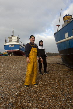 Fishermen Stuart Hamilton and Alfie White look out to sea after landing their catch on the beach at Hastings, East Sussex, UK. 19/12/21 Photo Tom Pilston