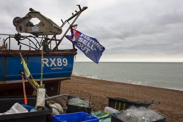A fishing boat flys a flag with the slogan 'No Fishing Sell Out' on the beach at Hastings.
