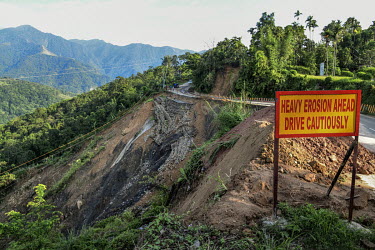A sign warning drivers to be cautious on a stretch of road which has partly collapsed due to a landslide.