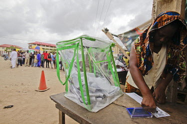 A woman thumb prints her choice of presidential candidate, while people queue behind. There is a high turnout to vote in the presidential election.