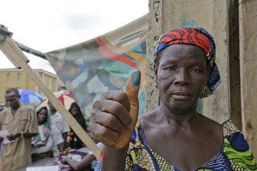 An elderly woman shows her inked thumb before casting her vote as Nigeria goes out to vote for the presidential election.