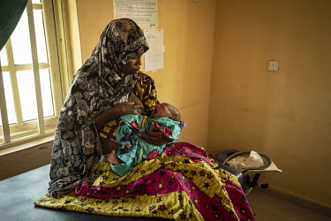 A woman breastfeeds her child at the clinic in the Teacher's Village IDP camp where she is receiving post-natal care. The camp is home to 20,000 civilians who fled the conflict with Boko Haram.