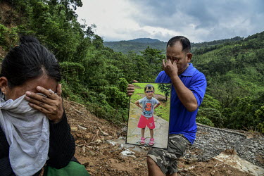 Keuheuningle Jeme (left) and, holding a photograph of his daughter, Pauheuchanhbe Jeme (right), the parents of Nchilungle Jeme (10), mourn at the place in Hoki Puonci village where their house once st...