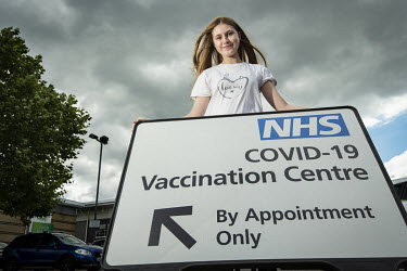 Carys Curtin (17) beside the COVID-19 vaccination centre sign at Chingford Leisure Centre. Carys has come for her first jab. The appointment was booked by her mother when, in August 2021, all 16 and 1...