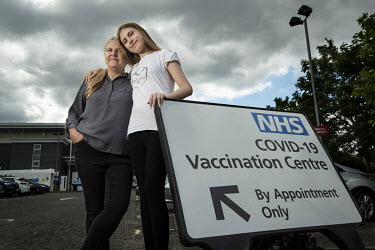 Carys Curtin (17) with her mother Cheryl Curtin (51) beside the COVID-19 vaccination centre sign at Chingford Leisure Centre. Carys has come for her first jab, which was booked by her mother. In Augus...