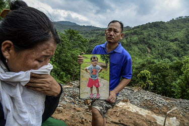 Keuheuningle Jeme (left) and, holding a photograph of his daughter, Pauheuchanhbe Jeme (right), the parents of Nchilungle Jeme (10), mourn at the place in Hoki Puonci village where their house once st...