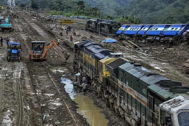 Workers trying to clear mud from a landslide that has derailed trains and stranded passengers after slipping from the top of hill above New Haflong station.