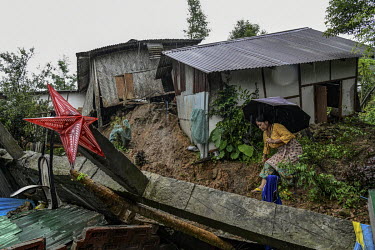 A resident examines damage to her house, in Gilgal village near Moulhoi, which was destroyed by a landslide.