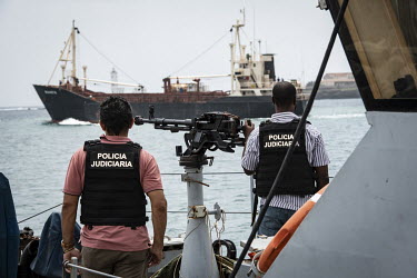 Police officers involved in the raid on the freighter Eser stand on an armed vessel. In February 2019, police on the island made the world's biggest-ever seizure of Europe-bound cocaine, when they fou...