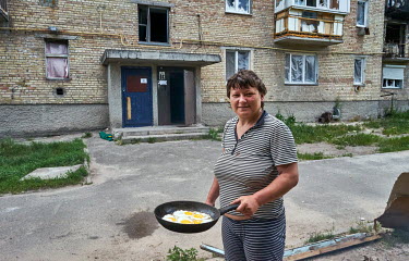 Karina cooking on an open fire set up in front of her apartment building on Sadova Street in Gorenka, a small village on the outskirts of Kyiv, which was shelled by Russian forces during the attack on...