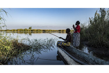 Women fishing on the banks of the Zambezi River which contains the parasite causing schistosomiasis (bilharzia).  Female Genital Schistosomiasis (FGS) is a waterborne parasitic disease affecting women...