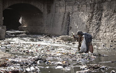 A drug addicted man searches for recyclable items, to pay for his habit, among the detritus beneath the Pul-e-Sukhta bridge (Pul-i-Sokhta).
