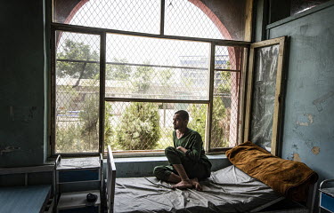 A patient looks out of a dormitory window onto the gardens of the Ibn Sina drug addiction hospital.