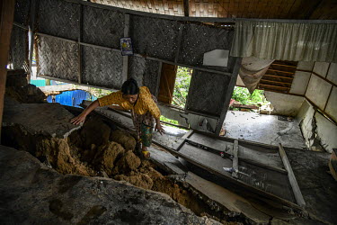 A resident examines damage to her house, in Gilgal village near Moulhoi, which was destroyed by a landslide.