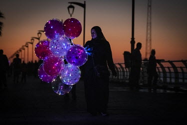 A woman sells balloons on Beirut's fashionable, and now unlit, corniche which has become the only place many can afford to visit for recreation in the city. The national grid is now providing only one...