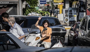 A scooter rider in a fuel queue.  Following political collapse and the pandemic, the Lebanese economy plunged, wiping out 90% of people's savings and resulting in massive inflation. The ammonium nitra...