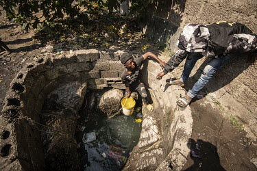 A youth pulls up a container of water from an open well in the Kanyama Compound (population 400,000). When the area floods, sewage seeps down into the well.Female Genital Schistosomiasis (FGS) is a wa...