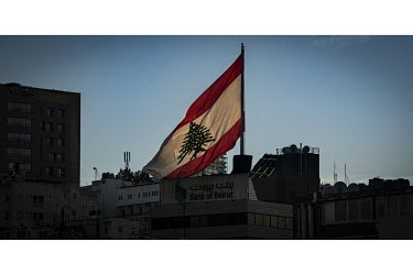 The national flag flies from the roof of a branch of the Bank of Beirut as night falls on the city which is largely left in darkness. Residents are lucky to receive two hours of electricity per day fr...