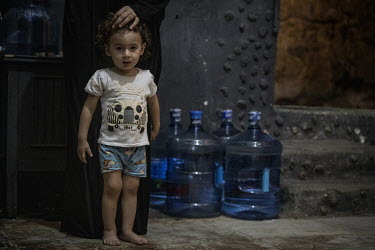 Fouad Ibrahim (13 months) stands near containers of drinking water that his family have delivered to the damp cellar where they live in Saida. Inflation surpassed 137 percent in August 2021 which make...