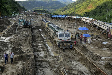 Workers trying to clear mud from a landslide that has derailed trains and stranded passengers after slipping from the top of hill above New Haflong station.