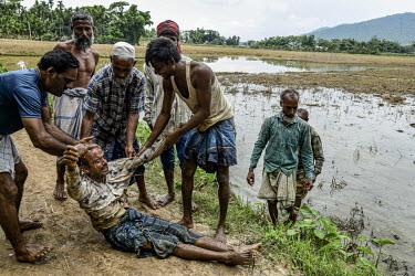 Fellow residents from Dekerua village help Hifjur Rehman (40), a third generation farmer, after he collapsed in despair while working to clear a rice paddy of its damaged crop which was destroyed by f...