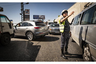 A police officer tries to control drivers in a long fuel queue.  Following political collapse and the pandemic, the Lebanese economy plunged, wiping out 90% of people's savings and resulting in massiv...