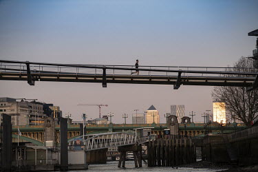 A man runs across the Millennium Bridge, spanning the River Thames during the coronavirus lockdown.