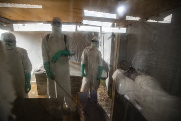 Medical staff prepare to bury Elodie Kitsama (19) who died from ebola the previous day at the Beni Ebola Treatment Centre. Her family look on from behind a protective window. Elodie, who was still at...