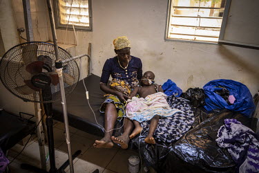 A woman comforts a child being treated at the Kaya Regional Hospital. The hospital is operating at over 100% capacity, often with three patients per bed.  Once considered 'safe', Burkina Faso (meaning...