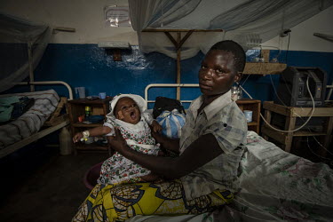 A woman holds a baby being treated at the MSF/UNICEF hospital.  There are at least 5.5 million internally displaced people (IDPs) in the DRC, mostly in the eastern provinces. In Ituri province alone t...