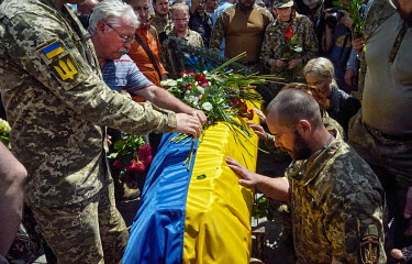Mourners at the farewell of the commander of the Carpathian Sich Battalion, Oleh Kutsin, place flowers on his coffin.