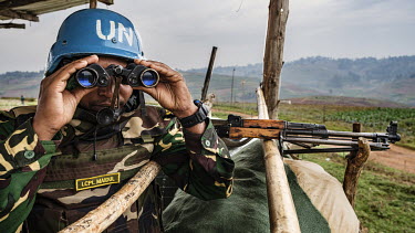 Lance Corporal Maidul, a MONUSCO (United Nations Organization Stabilization Mission in the Democratic Republic of the Congo) peacekeeper from Bangladesh looks through a pair of binoculars from his sec...