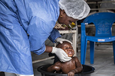 Nurse Eugenie Kabuya bathes Sandrine (22 months) in a basin in the UNICEF creche at the Ebola Treatment Centre in Butembo. Sandrine's mother is seriously unwell with Ebola although Sandrine has not te...