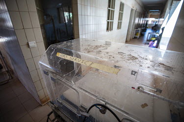 A broken neonatal incubator stands idle in a corridor at the Kaya Regional Hospital. The hospital is operating at over 100% capacity, in many cases there are three patients per bed.   Once considered...