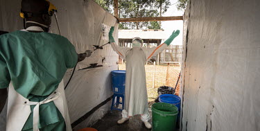 A colleague sprays hygienist Bertrand Karumba (33) with disinfectant as he leaves the Ebola treatment centre's treatment area.  An Ebola outbreak was declared on 7 February 2021 in Butembo less than a...