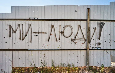 A fence in Horenka marked with shrapnel and grafitti that reads: we are people. Horenka is a small village on the outskirts of Kyiv, which was shelled by Russian forces during the attack on the capita...