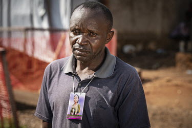 Alexis Kambale wearing a photograph of his sister Elodie Kitsama (19) on a lanyard around his neck during a family gathering at the mortuary to view her body after she died from ebola the previous day...