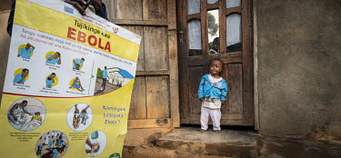 A child looks at a community health worker conducting house-to-house outreach educating the local population on the need for vaccinations.  An Ebola outbreak was declared on 7th February in Butembo,...